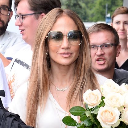 Jennifer Lopez wears a white dress with cage heels while arriving in Warsaw