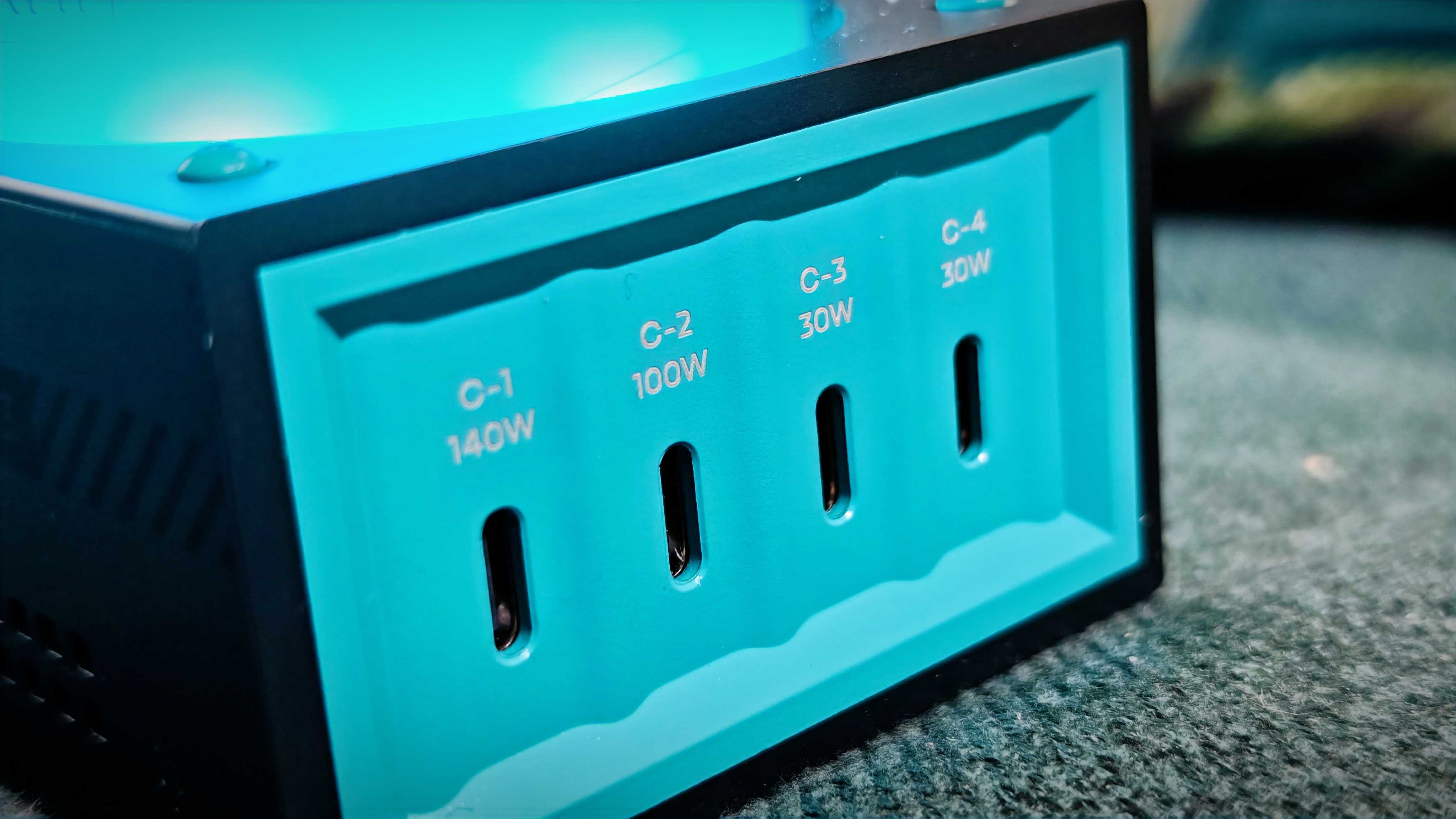 A grey-and-blue Genki Moonbase power strip and charging station sitting on a green sofa