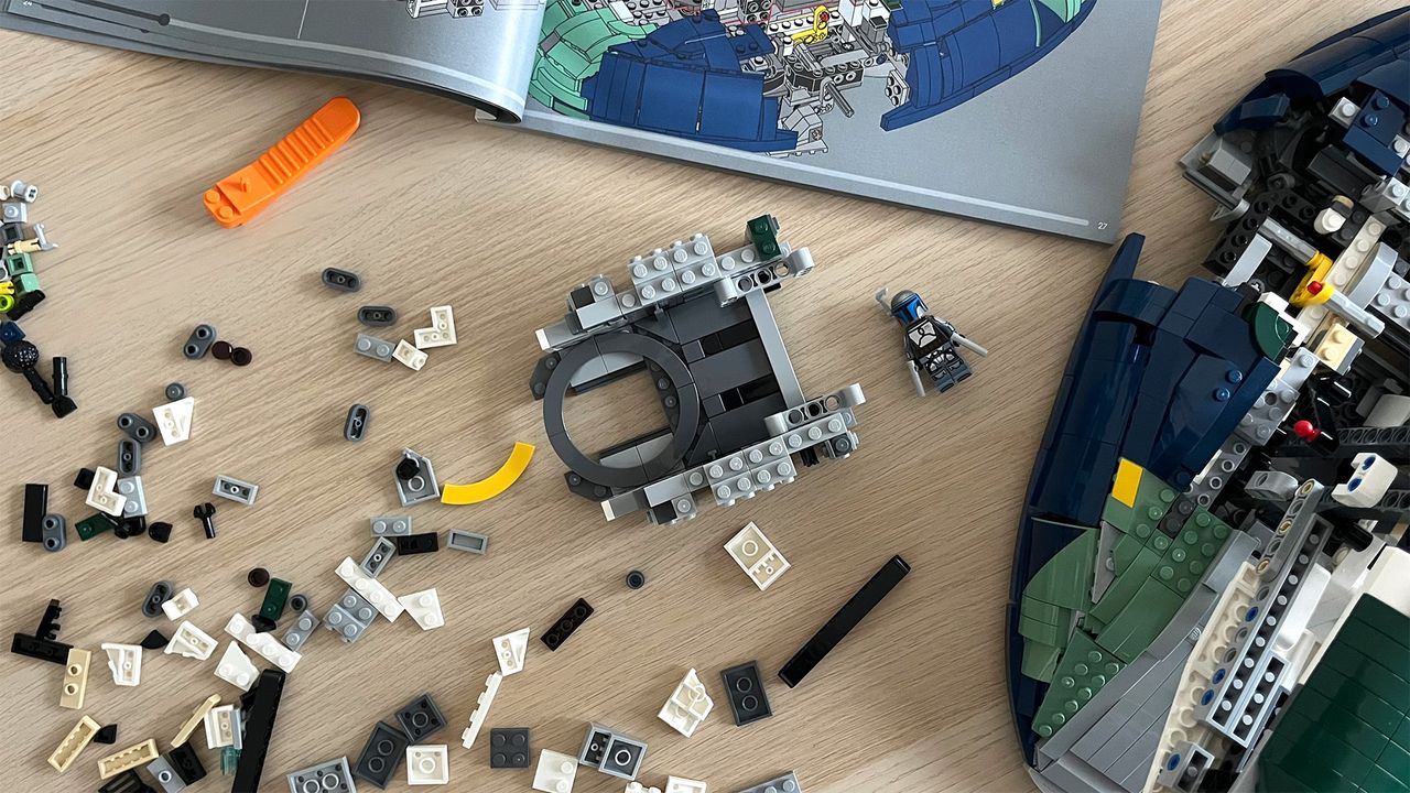Lego Star Wars UCS Jango Fett&rsquo;s Firespray-Class Starship (75409) mid-build on wooden tabletop next to lots of Lego pieces and an instruction booklet