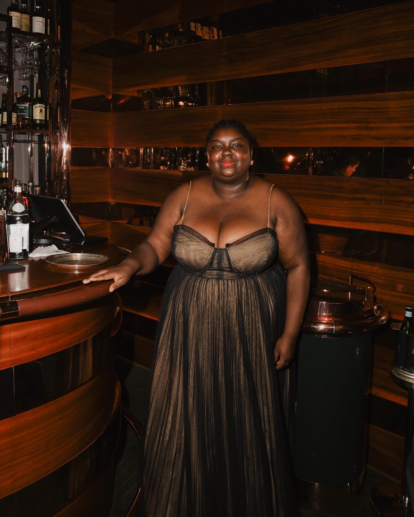 An image of @abimarvel wearing a sheer black dress, an example of one of the key party fashion trends for 2025.