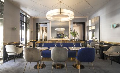 Dining room in grey and blue with brass features and mirrored surfaces