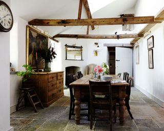 farmhouse dining room with beamed high ceiling, flagstone floors and wooden farmhouse table