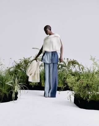 Woman in knitted jumper and trousers with plants