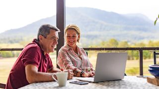 Ein Paar mittleren Alters, das glücklich aussieht, während es einen Windows 11 Laptop benutzt.