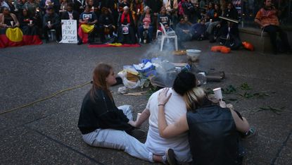 Supporters embrace around a fire during a vigil in Sydney