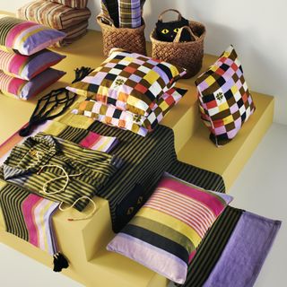 A selection of colorful home decor items, including throw pillows, baskets, and striped blankets