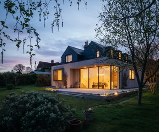 Timber-clad extension shown at dusk with lights shining through Kloeber's UberSlide doors.