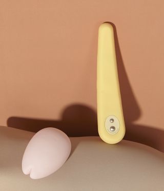 Peach neutral backdrop and curved shaped base, a yellow and a pale pink sex toy