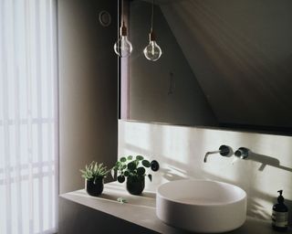 a bathroom with a round basin, black taps and wide mirror at dusk - claus-grunstaudl-I72dFJRFT3k-unsplash