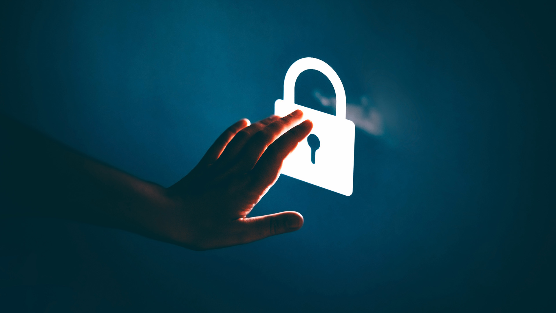 A hand touching a glowing white padlock in a dark environment, to represent living off the land cyber attacks.