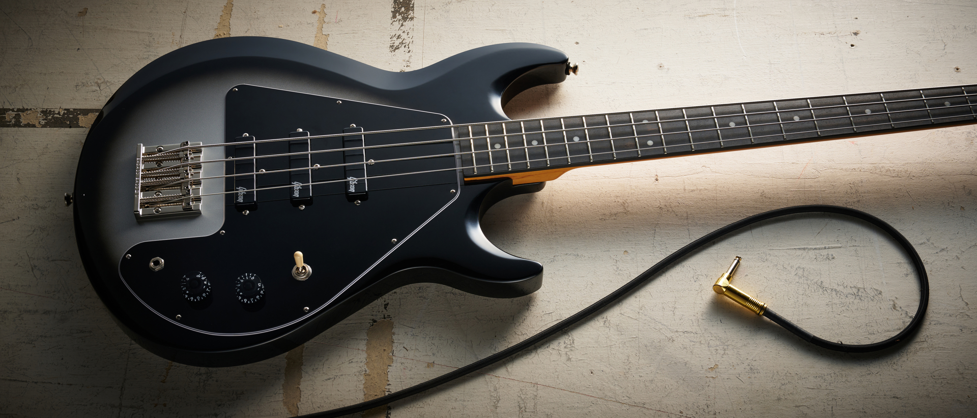 Epiphone Mike Dirnt Grabber G-3 in Silverburst finish photographed on scratched white board.