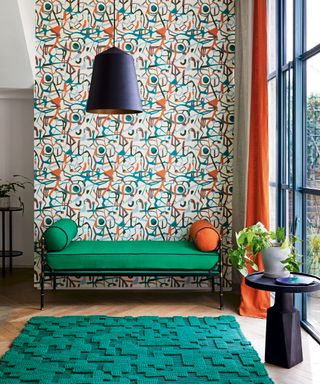 Modern entryway bench ideas with a green upholstered bench with orange cushion, green rug, green and orange wallpaper, and orange curtain