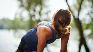 Close up of woman from behind doing a reverse plank outdoors