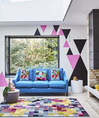 A modern living room with feature wall decorated with triangular motif and colorful rectangular area rug