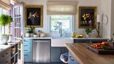 A white and blue kitchen with brass artwork frames on the walls and black hardware on the cabinets