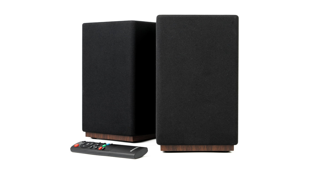 A pair of Roxel Infinity speakers in black and walnut, with a remote control in the foreground