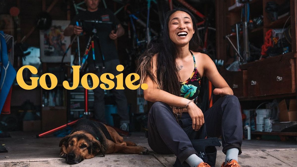 Go Josie film image, shows Josie Fouts laughing while sitting next to a dog