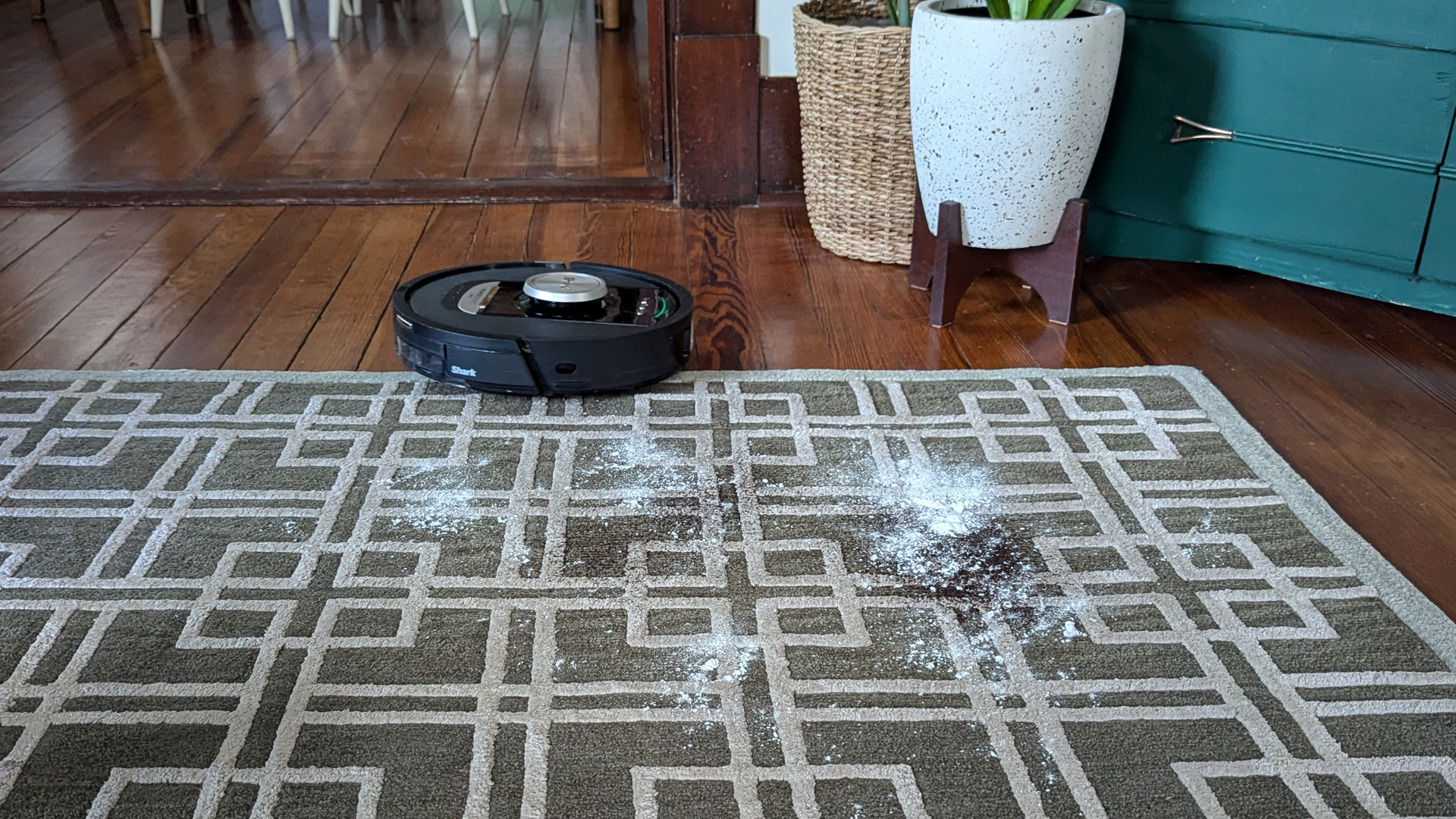 The Shark PowerDetect Robot Vacuum and Mop about to clean flour and coffee on a rug