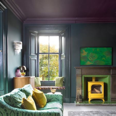 A living room with high dark purple-painted ceiling and dark teal walls