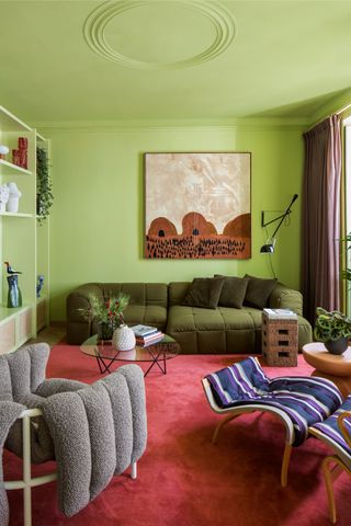 a lime green living room with a dark green sofa, a red carpeted floors and an orange artwork on the wall