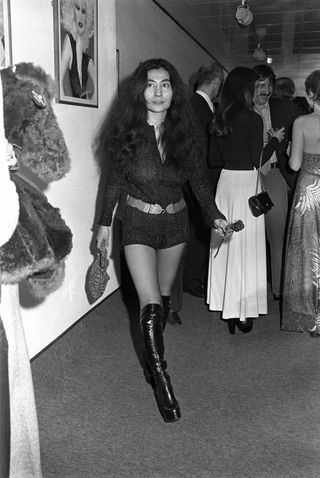 Japanese artist Yoko Ono wearing hot pants and platform go-go boots at an art gallery.
