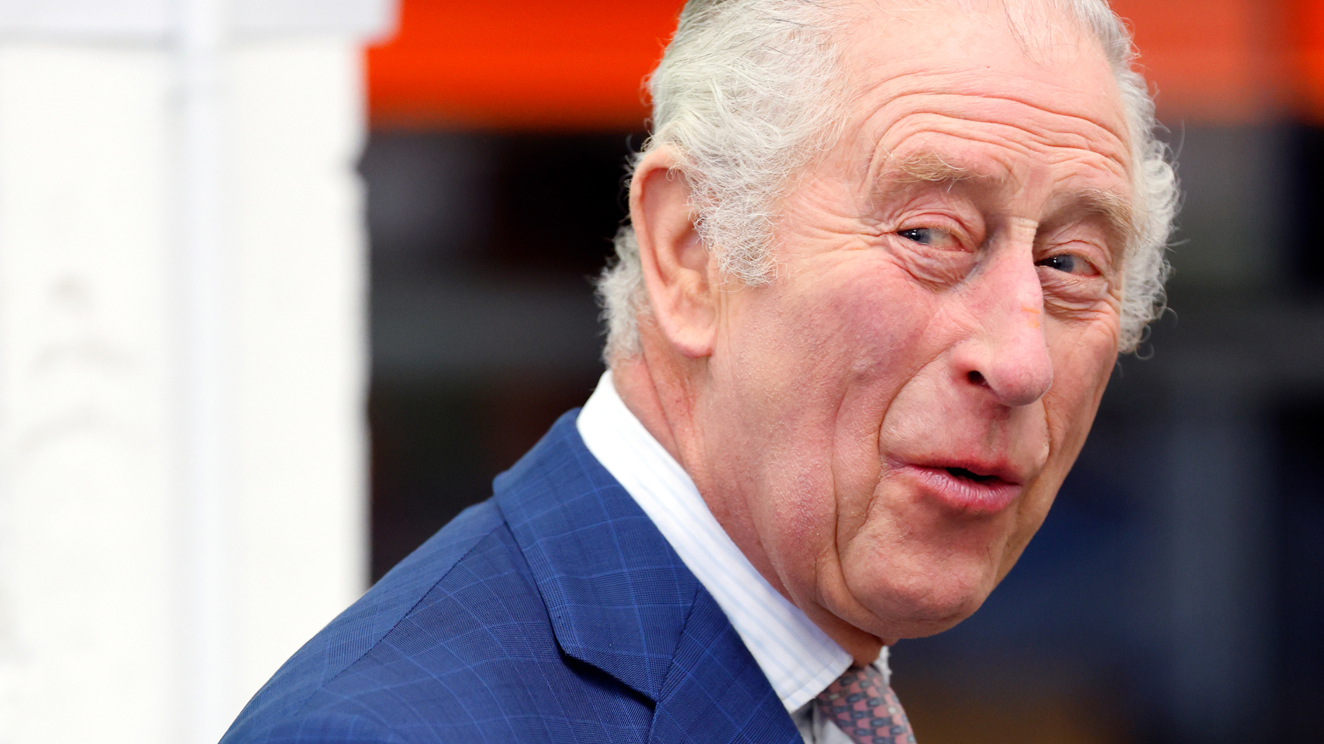 King Charles laughs while wearing a navy suit