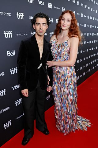 A photo of Sophie Turner attending a premiere in a feathered Louis Vuitton gown.