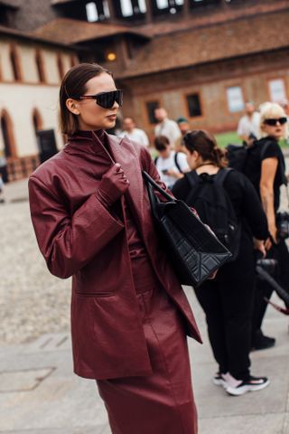 A woman at milan fashion week in red leather gloves and a red skirt suit