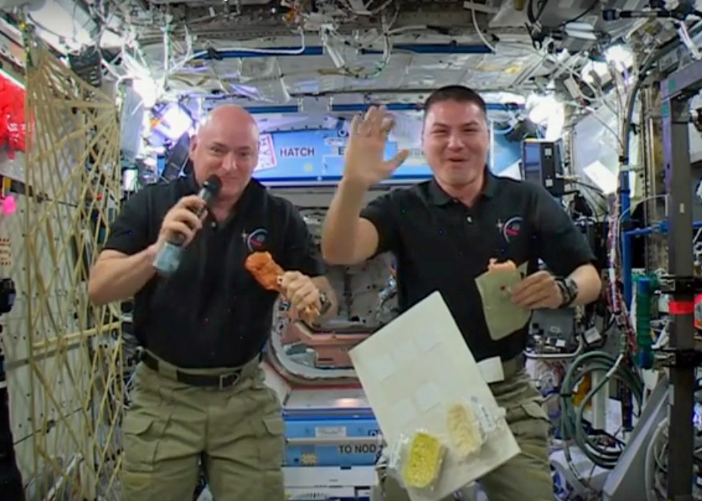 NASA astronauts Scott Kelly and Kjell Lindgren pose holding space-ified Thanksgiving staples aloft.