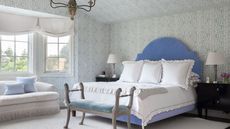 bedroom with blue headboard and light blue and white patterned wallpaper on walls and ceiling