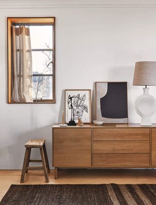 Wooden sideboard on a wooden floor, black rug and grey walls