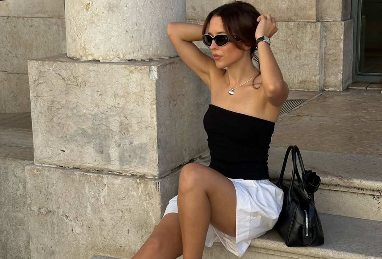 Débora Rosa wearing a black tube top, white shorts, and white tabis.