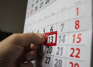 A close up of someone putting a red sticker round 13 on a calendar