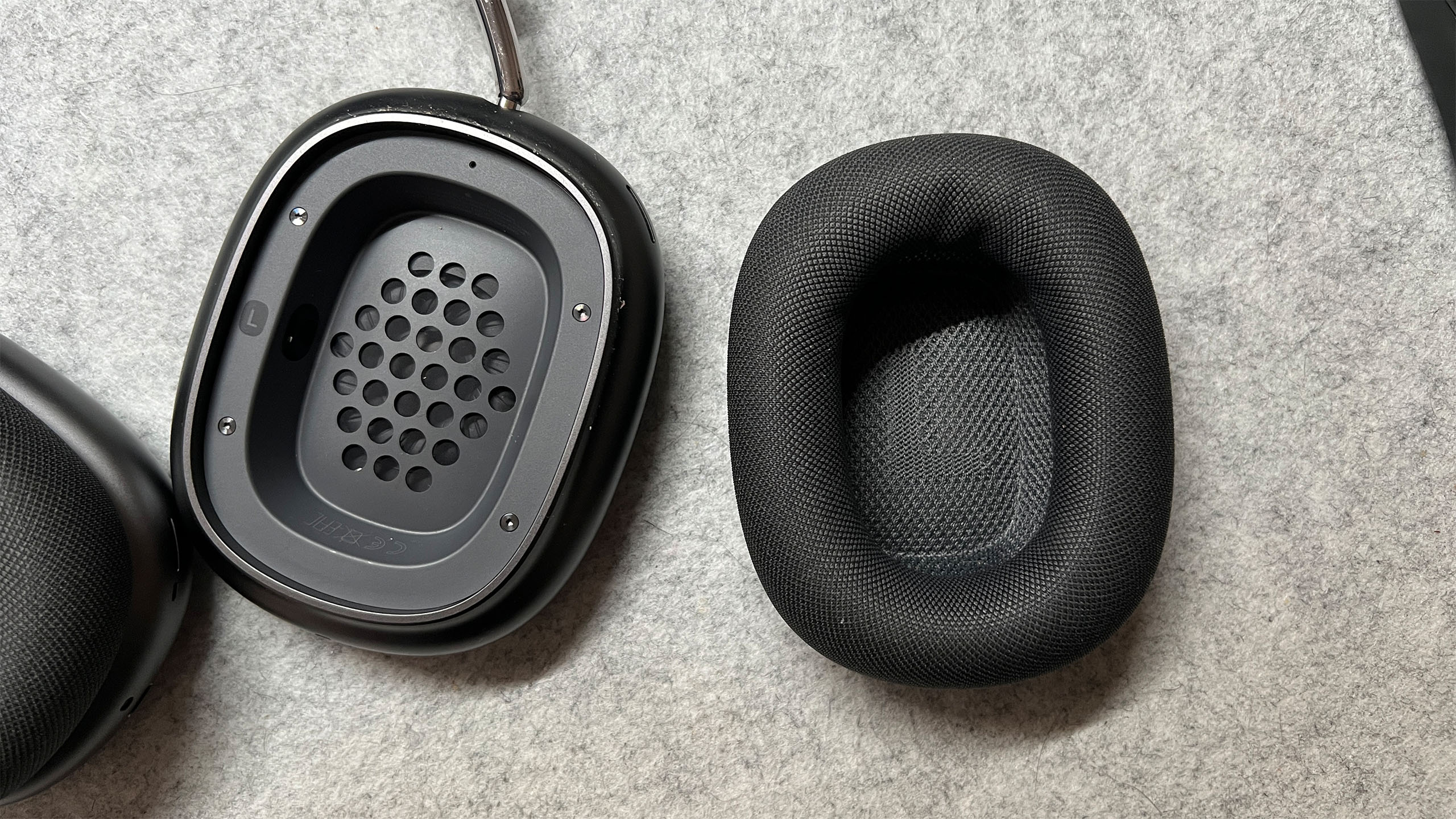 Apple AirPods Max dismantled showing the interior and exterior baffles of the headphones on a gray carpet