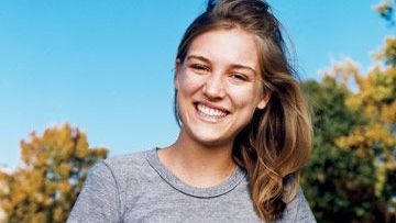 julia dewahl smiling in the park in a gray t shirt and workout pants