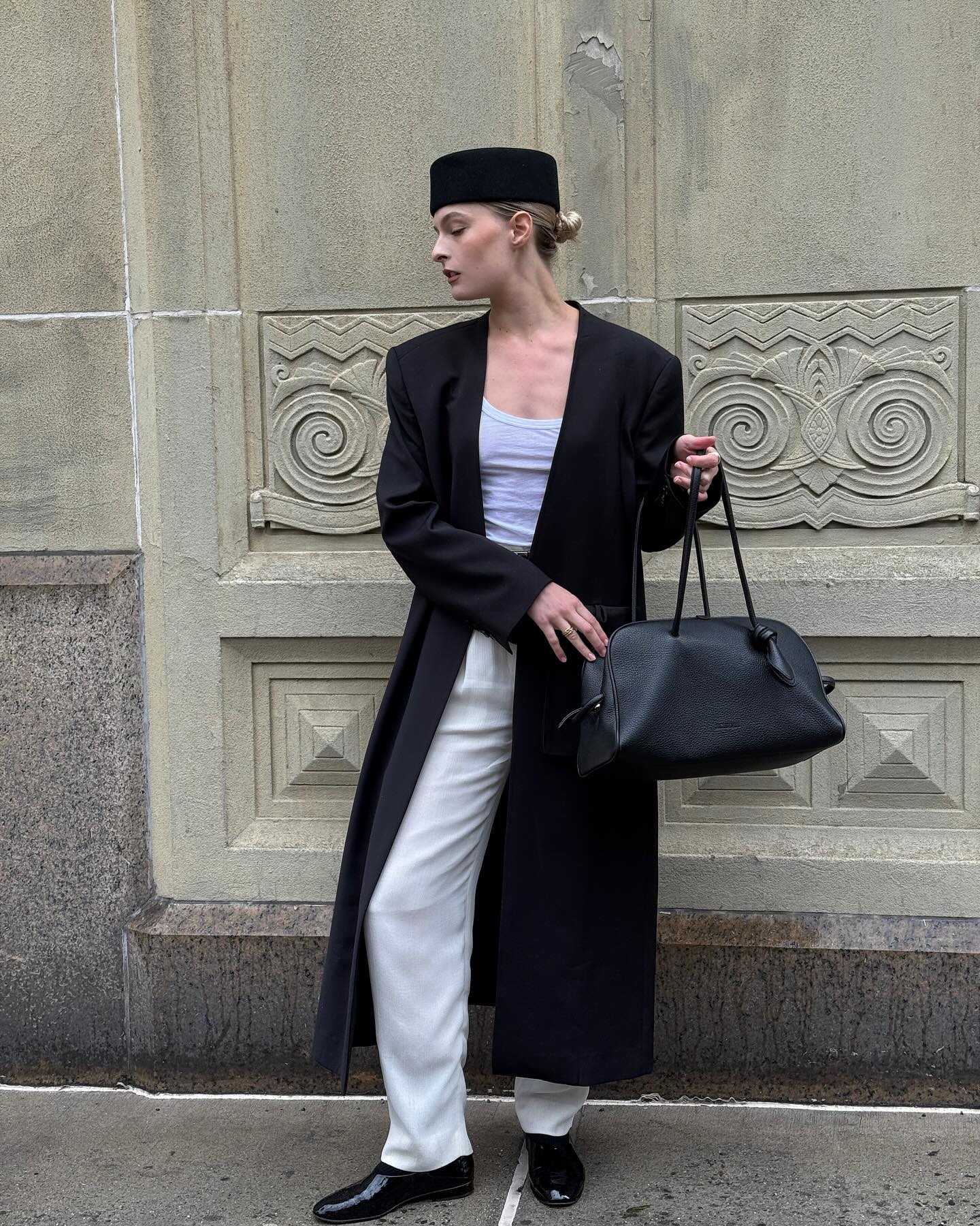 Woman on street in black coat, bag and hat