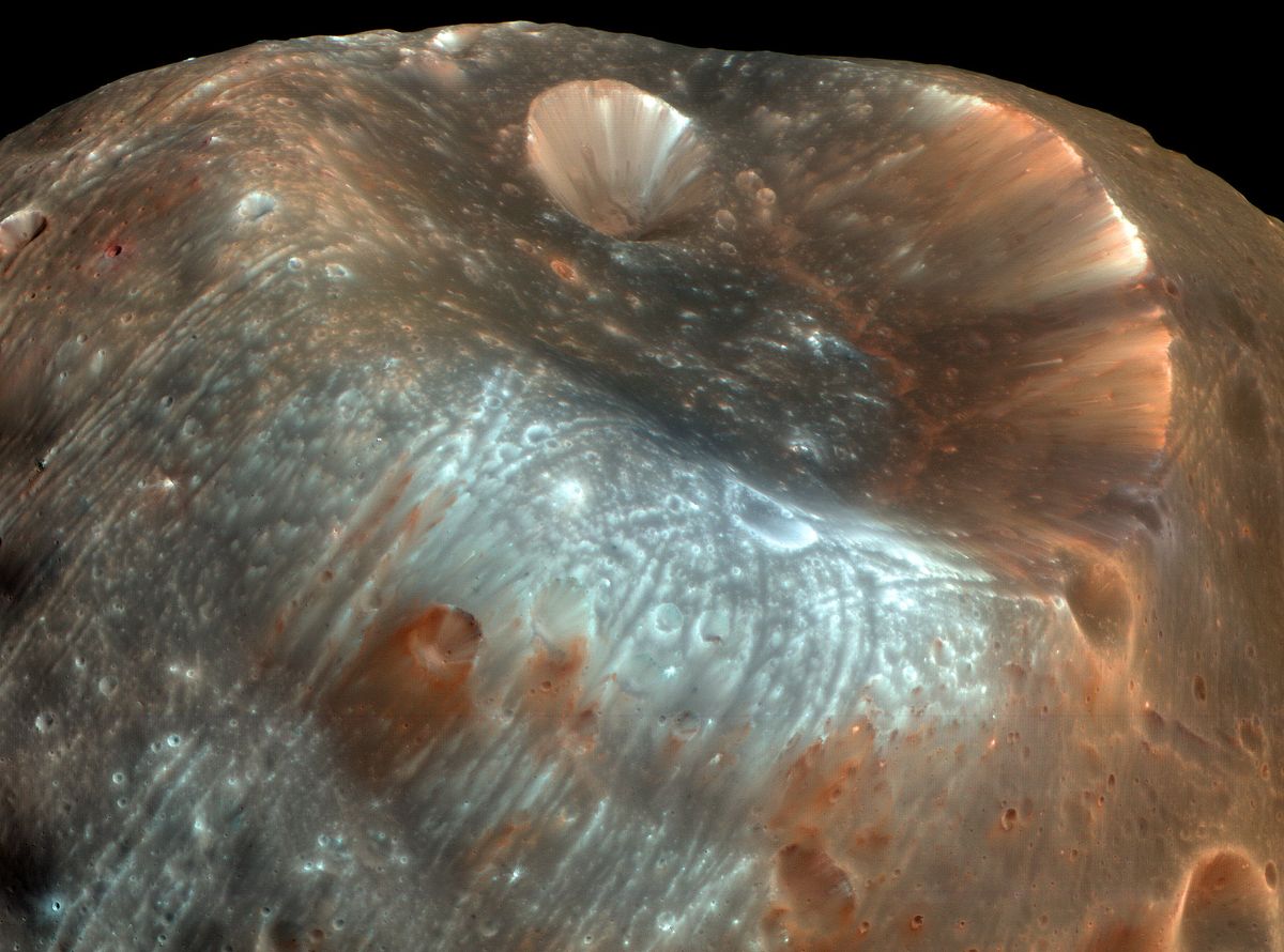 The massive Stickney Crater is the largest feature on the surface of Phobos. It stretches almost 6 miles (9.5 kilometers) at one end of the elongated moon, giving it the shape of a partially-deflated football. This color-enhanced photo was taken by the High Resolution Imaging Science Experiment (HiRISE) on NASA&#039;s Mars Reconaissance Orbiter 