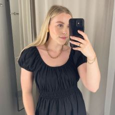 Woman wears black dress, gold jewellery