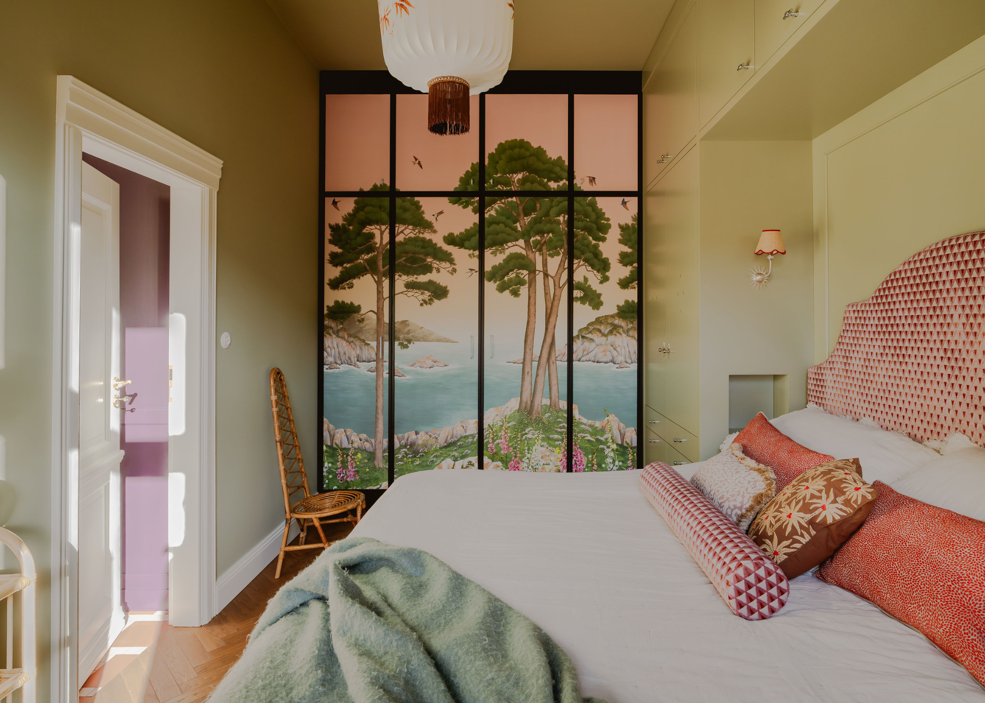 a small bedroom with green walls and a beautiful print screen on the far wall