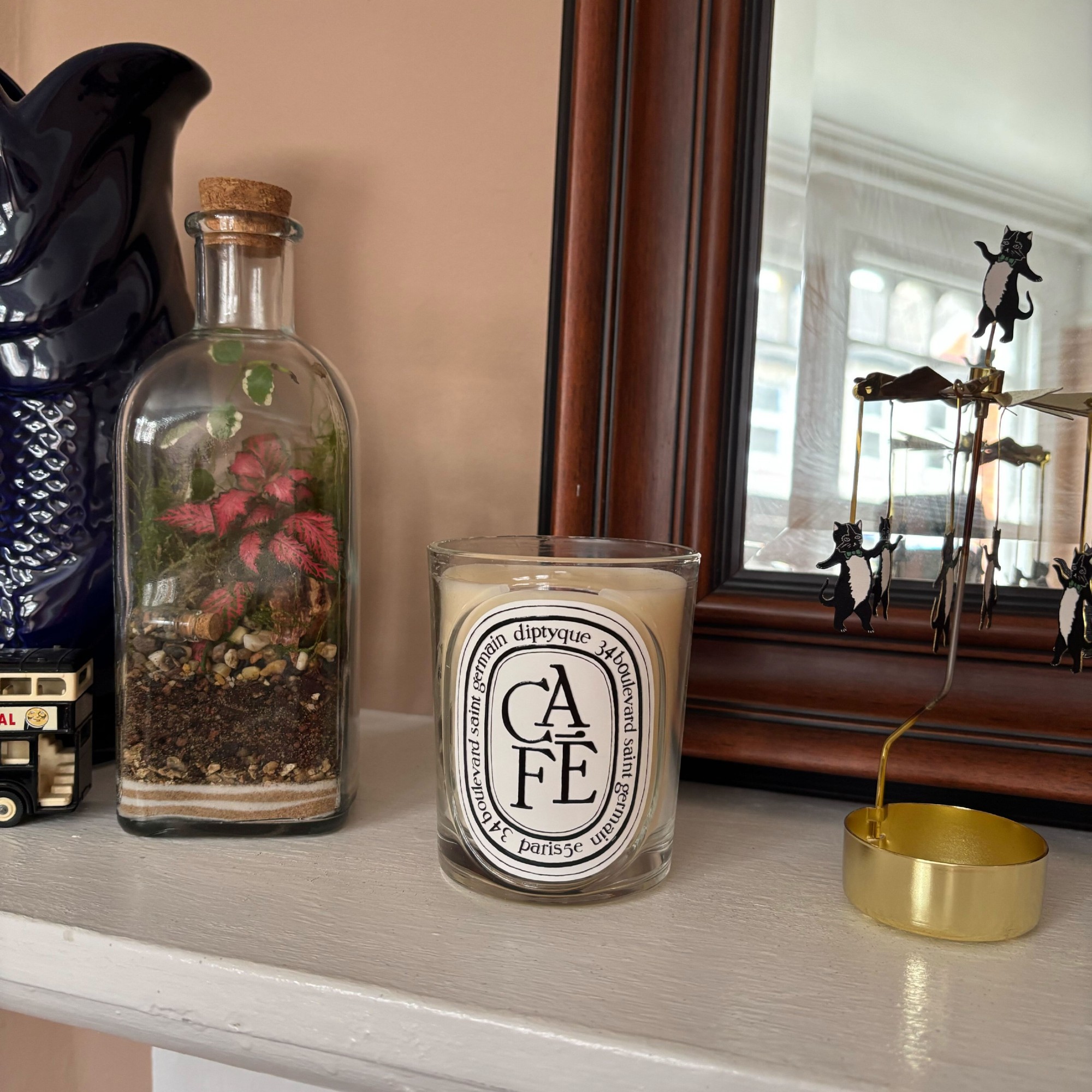 Diptyque's Cafe candle on Rebecca Knight's living room mantelpiece with a mirror and decorative objects