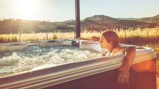 A woman relaxing in a hot tub at sunset