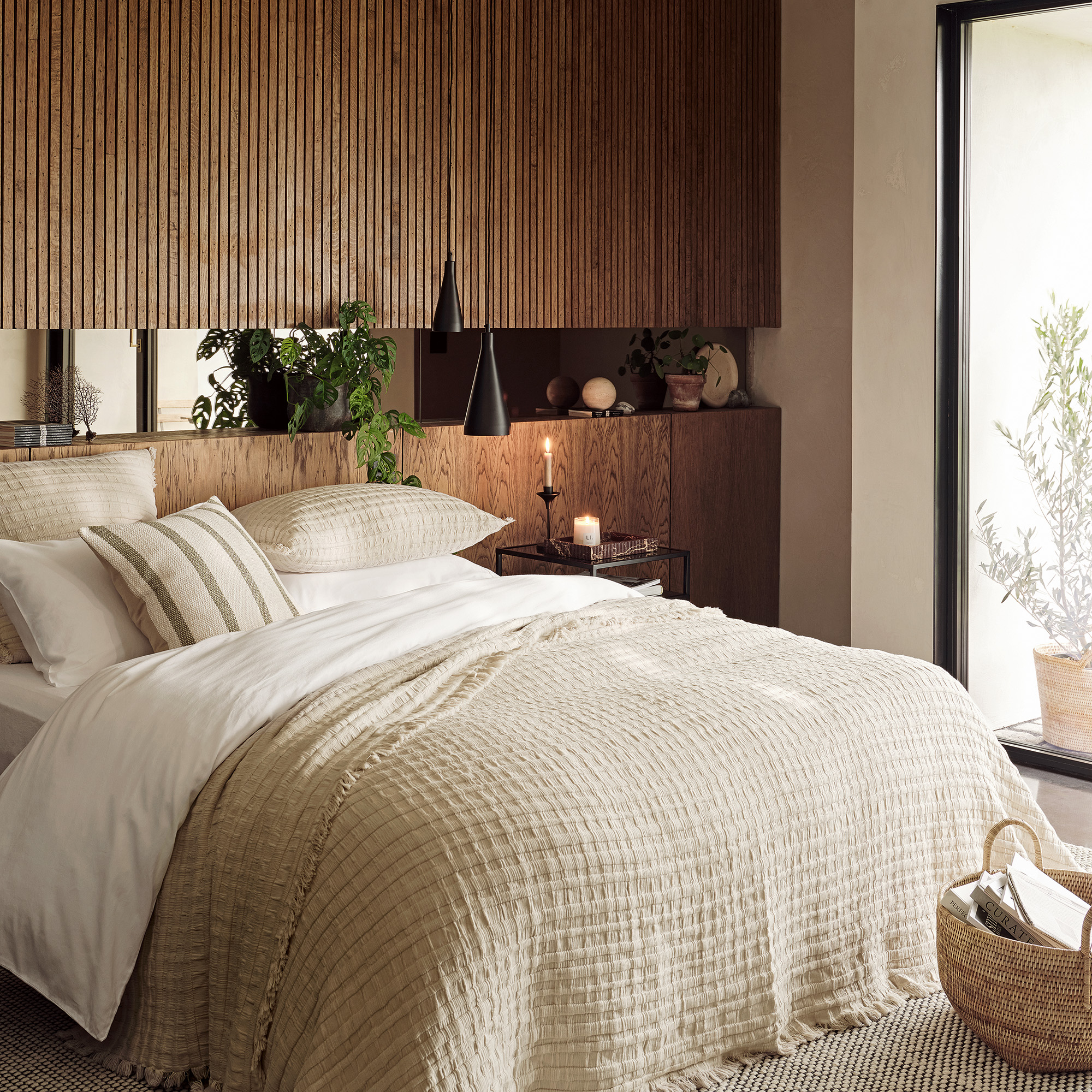 bedroom with fluted panelling at the top of the wall and solid wood planks on the lower half the bed is dressed in cream waffle cotton blanket and white cotton duvet cover