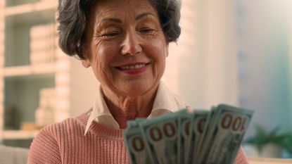 a happy woman holding a stack of one hundred dollar bills