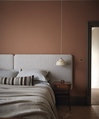 bedroom with brown painted walls and grey headboard and grey and blue neutral bedding