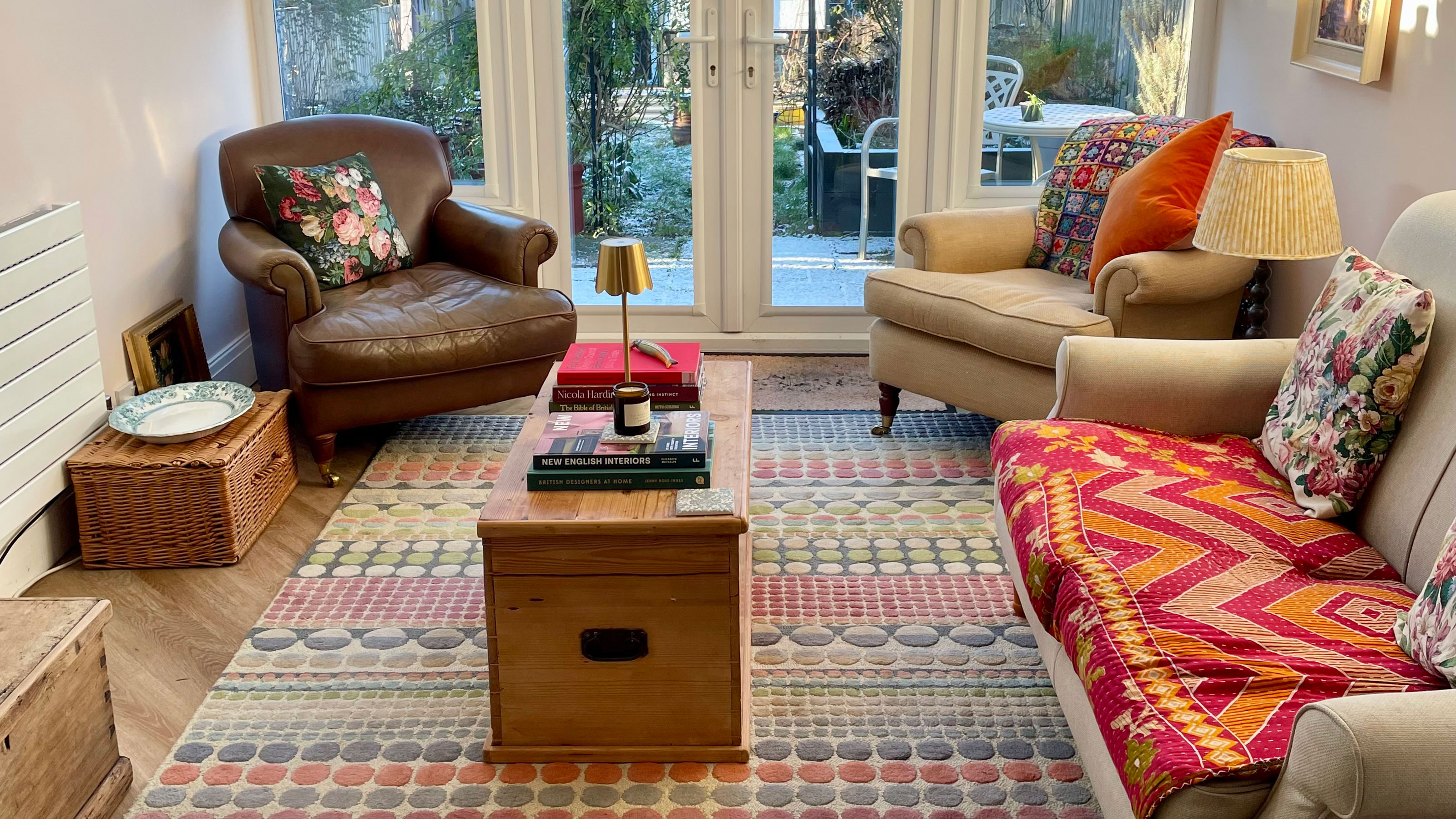 Living room with colourful rug, wooden coffee table, sofa and two armchairs