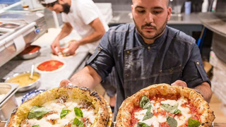 Michele Pascarella serves up two pizzas from his kitchen at the Napoli on the Road restaurant in Chiswick