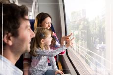 parents and child looking and pointing out of the window on a moving train