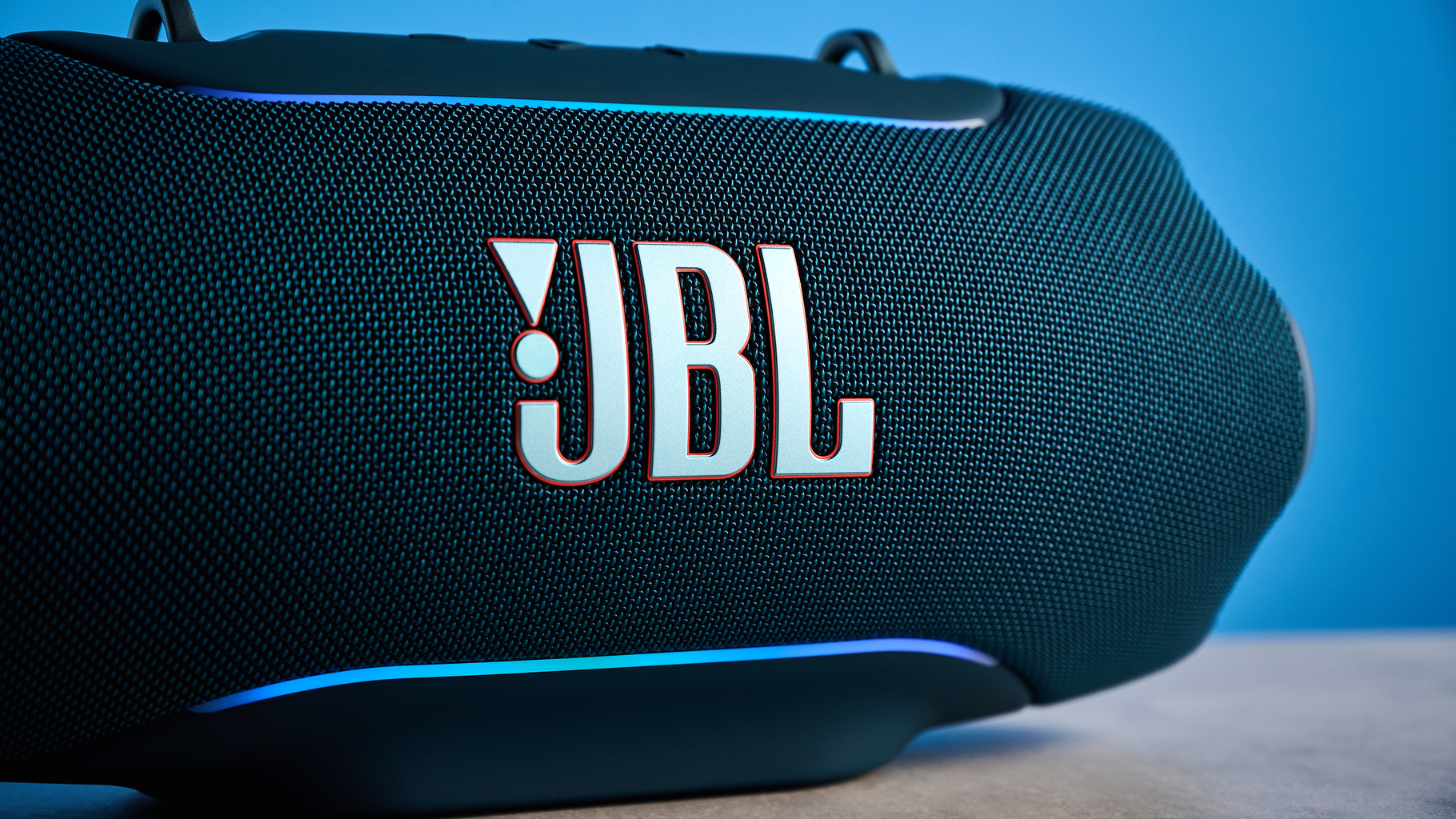the JBL Xtreme 5 bluetooth speaker in blue shown with the rugged carry strap and buttons
