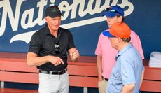 Greg Norman talks to Steve Cohen in the dug out of the New York Mets baseball team