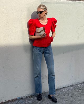 Elsa Hosk wearing a red top, jeans, and loafers.